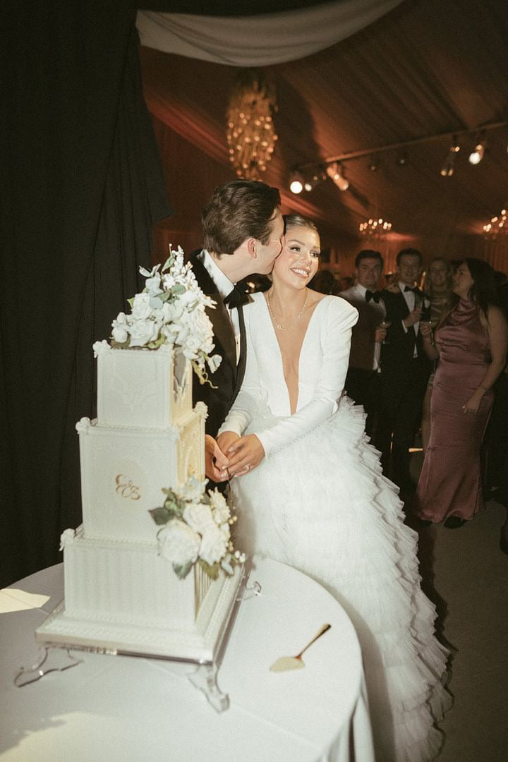 A glamorous couple captured cutting their stunning three tier wedding cake designed and made by The Frostery
