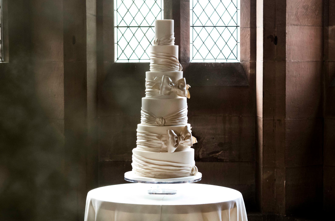 Six tier wedding cake with satin look sugar bow at Peckforton Castle in Cheshire