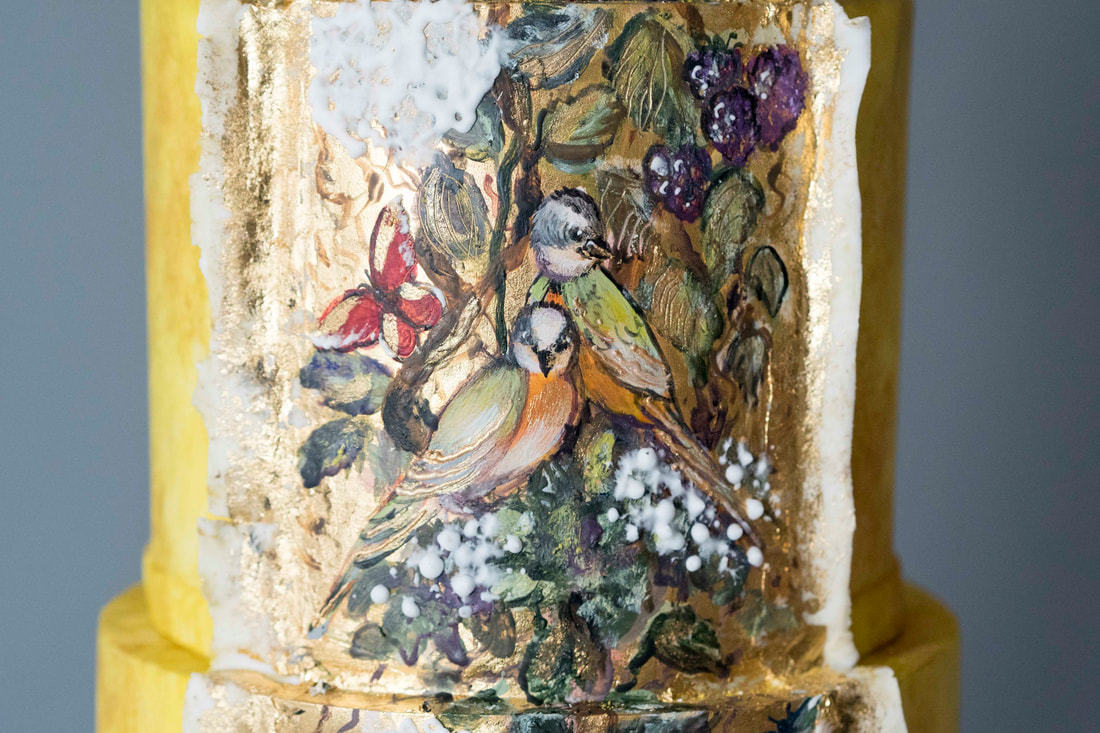 PictureSaffron yellow wedding cake with a hand-painted chinoiserie style panel featuring two love birds surrounded by summer fruits, birds and butterflies.