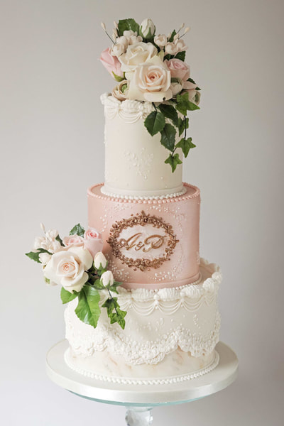 Three tier wedding cake with a shimmering pink middle-tier, royal iced detail and handmade sugar flowers made for a Liverpool wedding 