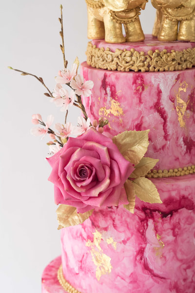 Close up of the single sugar rose in Magenta with gold leaves and sugar cherry blossom.
