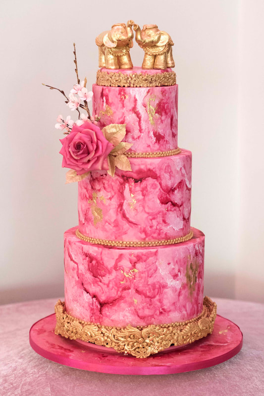 Magenta Ebru painted wedding cake with gold embellishments and gold elephants at Merrydale Manor, Cheshire