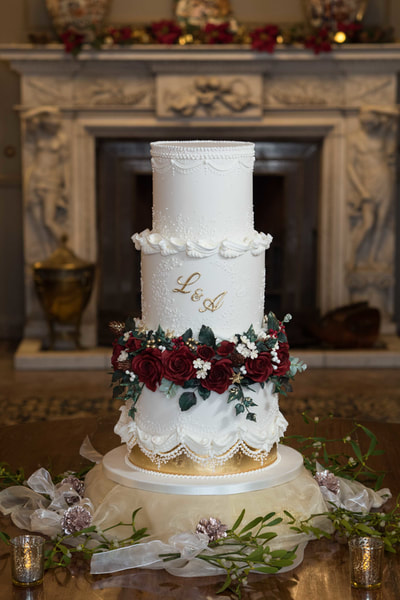 A Christmas themed wedding cake pictured  in front of a fireplace at Merseyside wedding venue, Thornton Manor, The Wirral