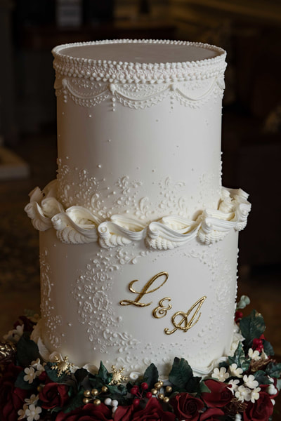 hand-piped royal icing scrolls and gold painted monogram feature on a three-tier wedding cake for a Cheshire wedding