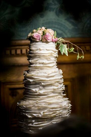 3 tier wedding cake with ruffles edged in edible gold leaf 