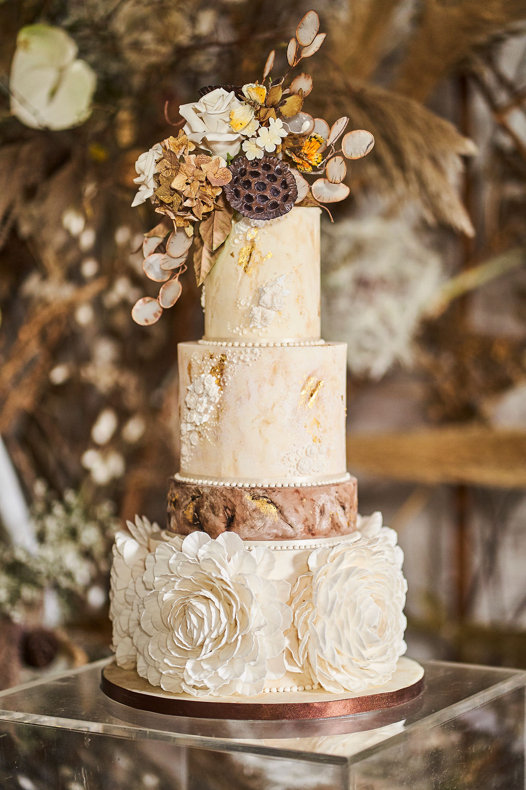 3 tier autumnal wedding cake with large white flower details, gold leaf, and sugar dried flowers