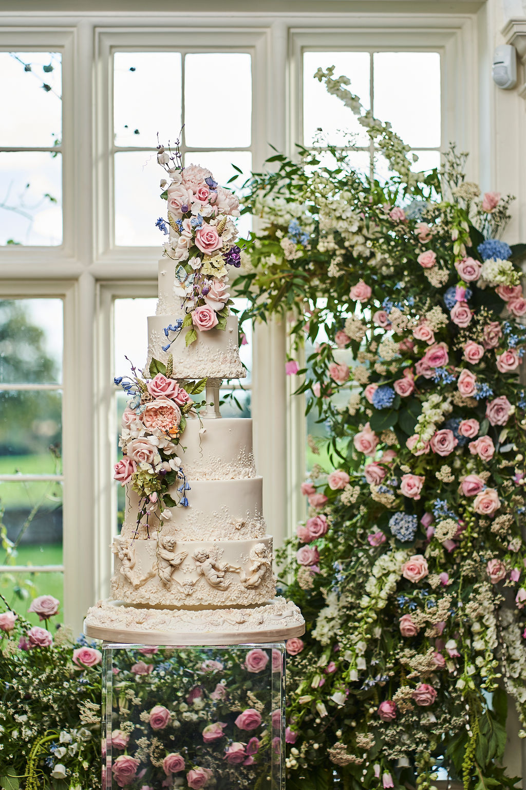 6 tier floral white wedding cake with cherubs, columns, and sugar flowers