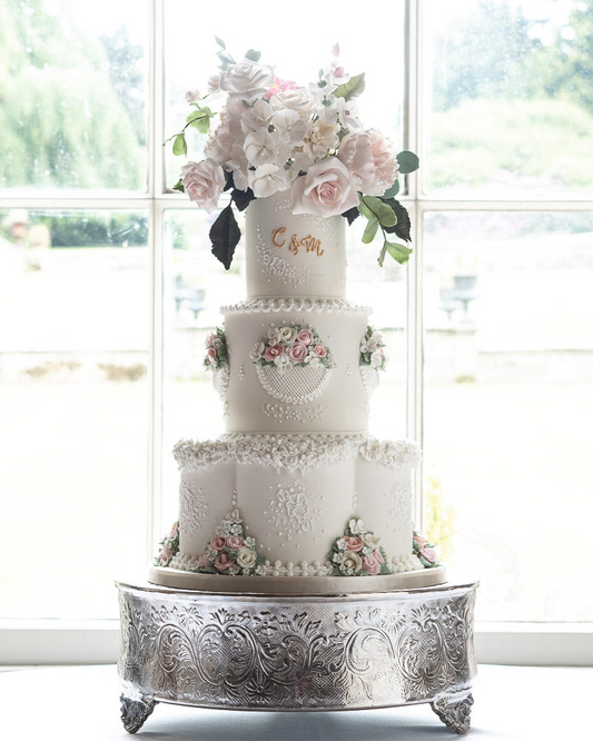 3 tier classic white wedding cake with pastel flower detailing, white textured trim, sugar flowers, and gold monogram 2