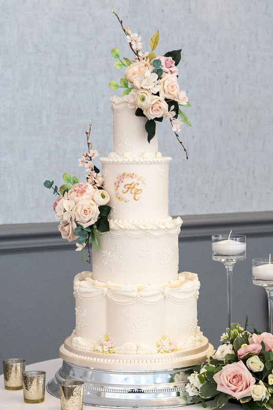 4 tier white extravagant wedding cake with hand piped trim, gold floral monogram and sugar flowers 41