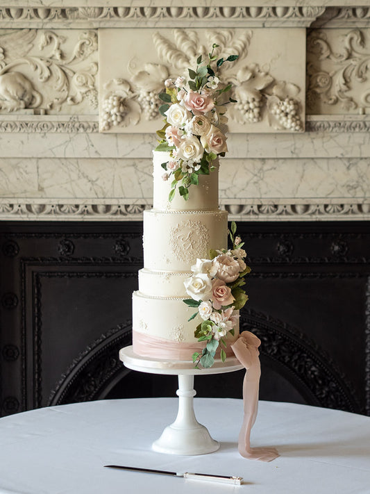 A romantic and elegant wedding cake showcasing the craftsmanship of a classic wedding cake in a modern design. Key design elements are the delicate monogram, sugar flowers and silk ribbon. 2