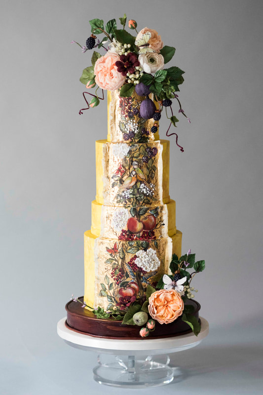 Saffron yellow wedding cake with a hand-painted chinoiserie style panel featuring two love birds surrounded by summer fruits, birds and butterflies.