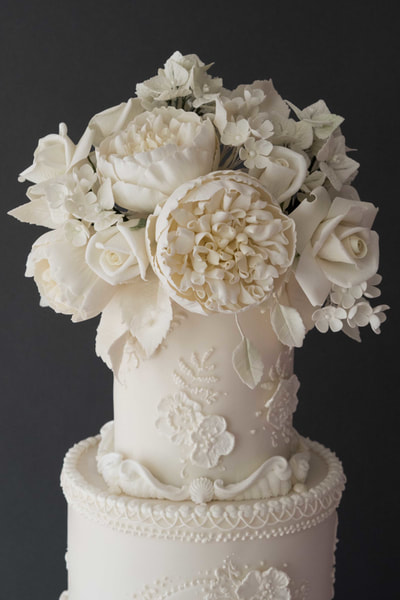 From a wedding at Cheshire's Peckforton Castle, here is a close up of the sugar flowers from this all white wedding cake design, inspired by the bride's beautifully seductive Pronovias wedding dress. 