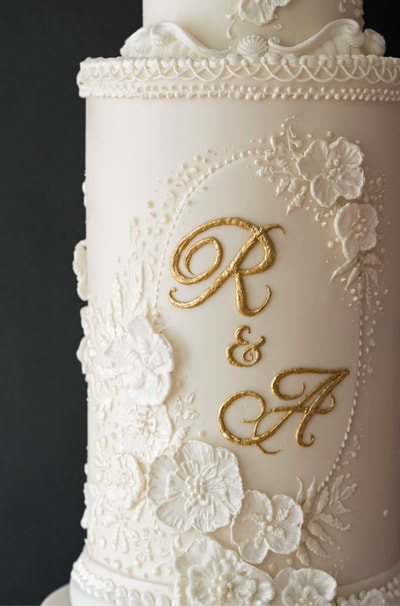 From a wedding at Cheshire's Peckforton Castle, here is a close up of the monogram and floral appliques from this all white wedding cake design, inspired by the bride's beautifully seductive Pronovias wedding dress. 